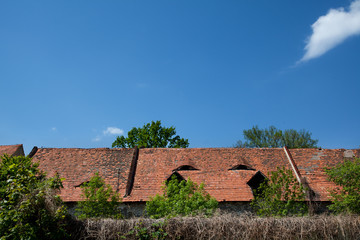 Fototapeta na wymiar Duża połać dachu ze starą dachówką na tle błękitnego nieba.