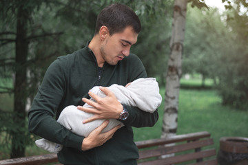 man with newborn baby in arms in Park, happy long-awaited fatherhood concept