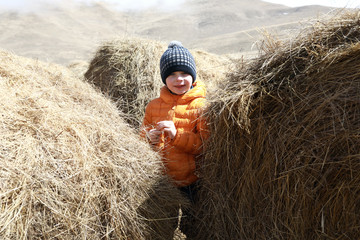 Child among hay bales on farm