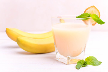 Banana juice in a glass with a slice of banana and mint