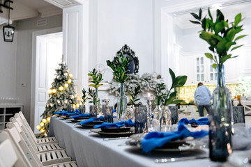 Beautifully decorated table in trendy colors with candles and green leaves. Professional serving for banquet. Close up of details.