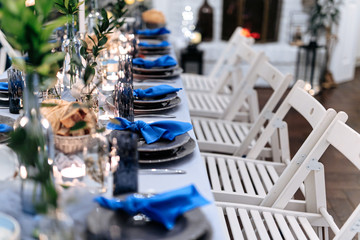 Close up of long table decorated and served professionally for celebration with white chairs in row. Beautiful details. Combination of trendy colors.