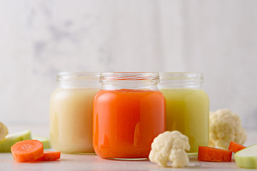 baby vegetable puree of carrots, zucchini, cauliflower in glass jars on white background, baby food concept