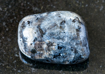 closeup of sample of natural mineral from geological collection - polished Larvikite (norwegian Labradorite) rock on black granite background from Norway