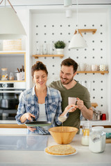 Young couple making pancakes together at home. Loving couple having fun while cooking.	