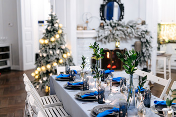 Table setting with glasses, plates, cutlery, napkins in white and blue trendy colors. Close up of beautiful decoration. Celebration of christmas eve.