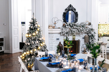 Beautiful living room with fireplace, christmas tree and festive table. Christmas decoration in classic blue and white colors.