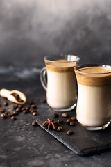 Two glass cups with Dalgona frothy coffee trend korean drink latte espresso with coffee foam on black background