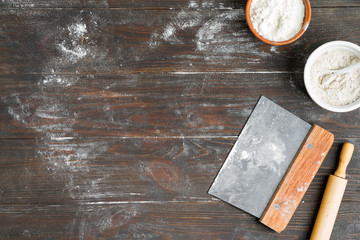 Background with ingredients for preparing fresh homemade dough on a gark brown wooden background.