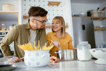 Young couple making delicious food at home. Loving couple enjoying in kitchen..	