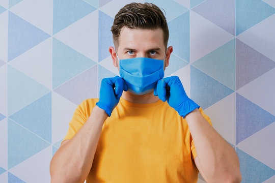 white man with nitrile gloves wearing a blue surgical mask