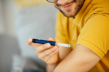 Young man giving himself an insulin shot at home
