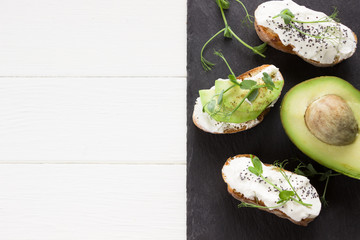 Healthy sandwiches with avocado , cream cheese and micro green. Vegan sandwiches, vegan food, healthy eating. Template with space for text , black background