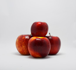 four red, ripe apples stacked in a pyramid on a white background. apples are a source of vitamins and iron during the period of quarantine and self-isolation