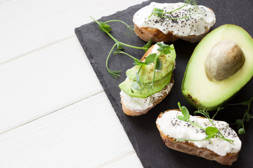Healthy sandwiches with avocado , cream cheese and micro green. Vegan sandwiches, vegan food, healthy eating. Template with space for text , black  and white background