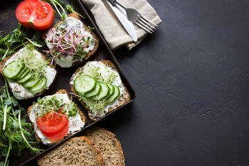 Healthy sandwiches with cream cheese , microgreens, tomatoes and cucumber. Healthy eating, diet food, vegan food, healthy breakfast.Black background, empty template