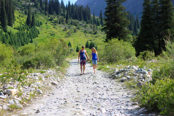 Joy of love. A loving blonde girl holds the hand of a handsome man. Walk along the mountain gorge, Ala Archa national park, Kyrgyzstan.