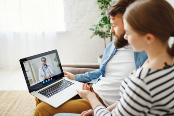 Couple listening to therapist during online psychotherapy session.