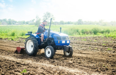 Obraz premium A farmer on a tractor works on the field. Growing crops in a small agricultural family enterprise. Small business support. Farming and agriculture. Cultivation technology equipment. Food production