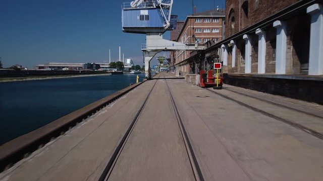 Drone flying backwards just above ground in an urban industrial empty of people harbour working area