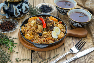 pilaf with lamb meat, dried fruits, dates and walnuts, on a wooden table
