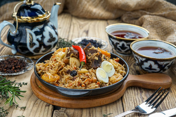 pilaf with lamb meat, dried fruits, dates and walnuts, on a wooden table