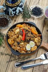 Fototapeta na wymiar pilaf with lamb meat, dried fruits, dates and walnuts, on a wooden table