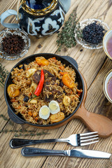 pilaf with lamb meat, dried fruits, dates and walnuts, on a wooden table