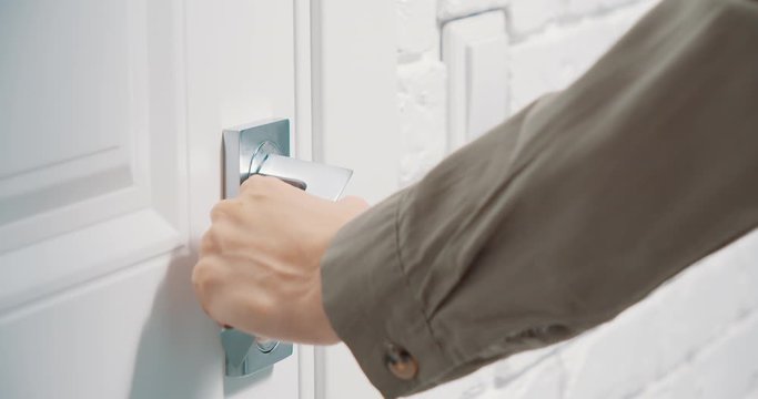 Close up of female hands opening a white door with a metal handle