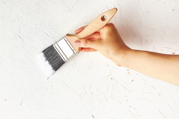 Female hand painting with brush wall surface.