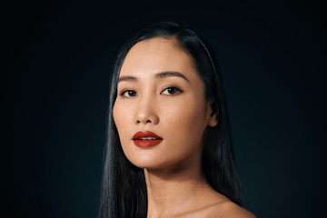 The sexy strict woman with makeup and a fashionable hairstyle poses in studio on black background