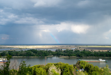 Fototapeta premium rainbow in the sky over the river, barges are anchored.
