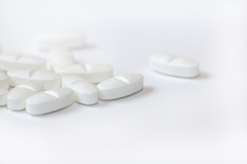 White pills on a white background close-up. Painkillers. A remedy for the Covid19 virus. Tablet macro. Copy space.