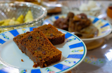 2 slices of delicious home-made fruit cake on plate. Contain some noise or grain and soft focus given indoor light. Selective focus.