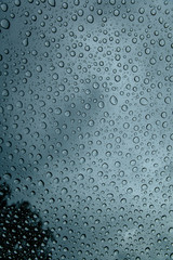 Natural pattern of water drops on window glass during rainy weather. Texture wallpaper and backdrop. Close up, space for text.