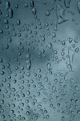 Abstract background of window glass with raindrops falling down. Texture wallpaper and backdrop. Close up, space for text.