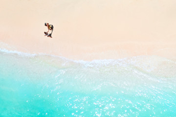 A couple walks along the Beach of Mauritius in the Indian ocean. Top view of the beach with...