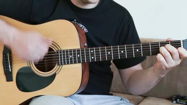guy playing an acoustic six-string guitar. learning to play a musical instrument close-up.