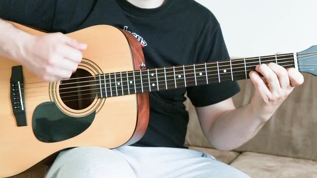 guy playing an acoustic six-string guitar. learning to play a musical instrument close-up.