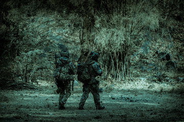 The action soldiers walking hold weapons with smoke light at night time background.