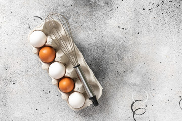 Eggs in a tray on the kitchen table. White and brown eggs with a whisk in the tray. Chicken eggs...