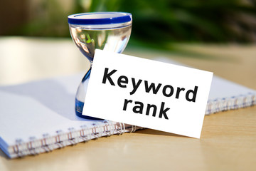 Keyword rank for seo website - business concept text on a white notebook and hourglass clock, green leaves of flowers