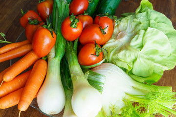 Healthy nutrition with fresh raw vegetables: a low angle close up view of a group of salad ingredients, lettuce, tomatoes, cucumbers, fennel, spring onions, and carrots