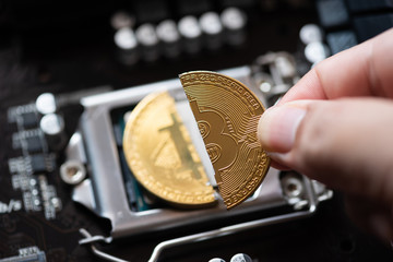 man hand pick up Cryptocurrency bitcoin with cutting traces in the middle on computer mainboard....