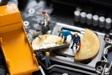 miniature people cutting cryptocurrency bitcoin on mainboard CPU. sign of bitcoin halving concept