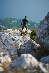 Hiker from behind standing in mountains at the edge of a cliff under the sea.