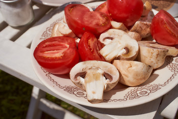 Vegetables for grilling tomatoes and mushrooms on a white plate