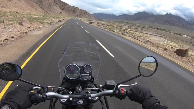 A sunny day point of view shot of casually riding sports bike over a well built road in barren mountains of Ladakh,India close to China Tibet border. Shot using an action cam mounted over helmet