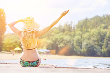 Junge Frau im Bikini beim Sonnen am Steg im Sommer