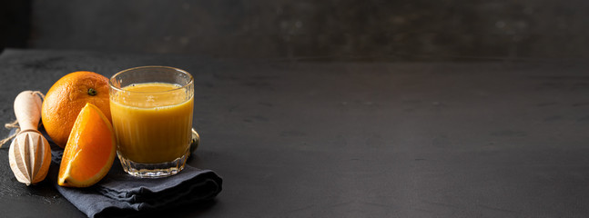 Orange juice, orange fruit  and wood citrus squeezer on dark background. Making natural juice...
